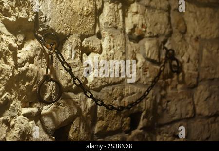 Slavery and bondage strong steel old shackles on stone wall in castle cellar or tomb Stock Photo