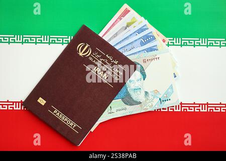 Red Islamic Republic of Iran passport and iranian reals money bills background close up. Tourism and travel concept Stock Photo