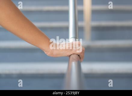Close up shoot on a hand catching a stair rail. Woman aware about safety while walking on the stair way. Walking up or go down. Stock Photo
