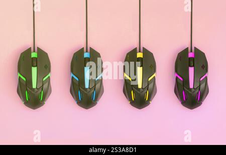 Several computer mice hang on a pastel pink background. The concept of cooperative computer video games, the use of auto-clicker and pay-per-click Stock Photo