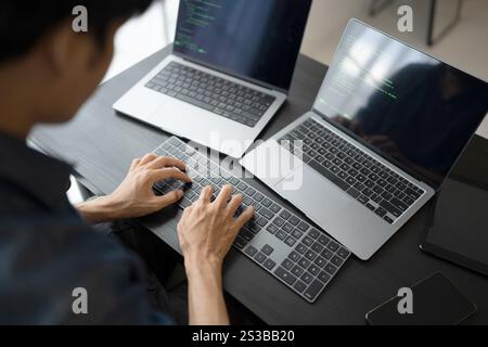 Asian man software engineer Working on Computer at office desk for writing program code IT Software Engineer finding errors tech support devops Stock Photo