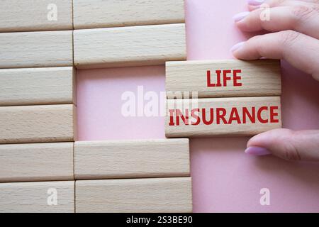 Life insurance symbol. Concept word Life insurance on wooden blocks. Businessman hand. Beautiful pink background. Business and Life insurance concept. Stock Photo