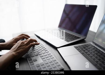 Asian man software engineer Working on Computer at office desk for writing program code IT Software Engineer finding errors tech support devops Stock Photo