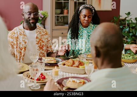 African American married couple sitting at holiday table holding hands while praying together Stock Photo