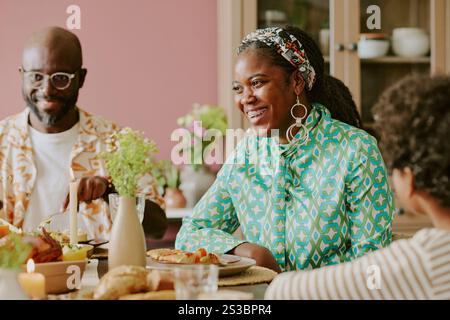 Medium close up of smiling and beautiful African American woman laughing while celebrating holiday with family Stock Photo