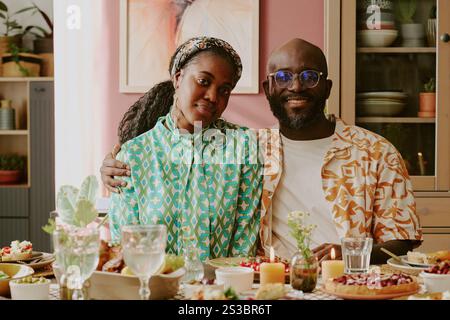 Medium close up portrait of young African American couple sitting at table with festive food Stock Photo