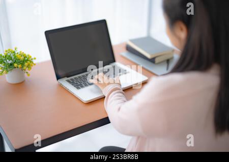 Pregnant asian woman using laptop at home pregnant businesswoman typing on laptop working on remote project in home office pregnancy concept Stock Photo