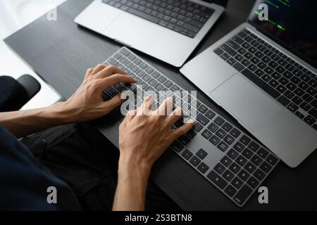 Asian man software engineer Working on Computer at office desk for writing program code IT Software Engineer finding errors tech support devops Stock Photo