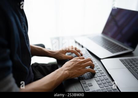 Asian man software engineer Working on Computer at office desk for writing program code IT Software Engineer finding errors tech support devops Stock Photo