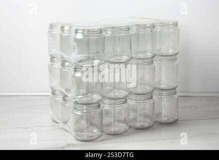 A pile of empty clean packed glass jars on top of each other. In room, white background. Stock Photo