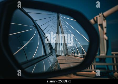 The Rion-Antirion Bridge in Greece, reflected in a car's side mirror. The symmetrical cables and towering pylons create a striking geometric design Stock Photo