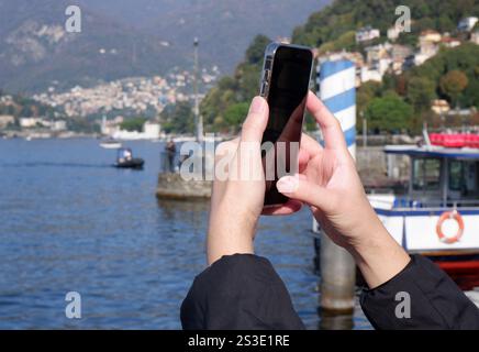 woman taking a picture with smartphone of Lake Como in Como, Lombardy, Italy Stock Photo