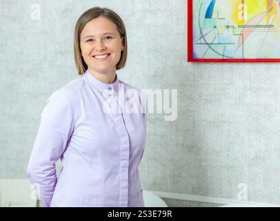 Smiling professional dentist posing confidently in her modern office, showcasing expertise in dental care and patient service Stock Photo
