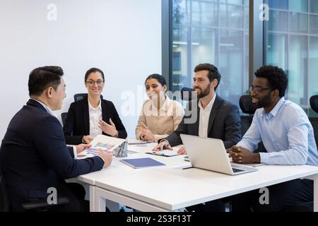 Diverse business meeting of colleagues, people sitting at table in conference room inside company office, discussing business project and new startups. Stock Photo