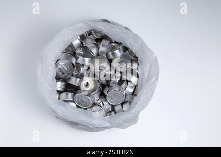 Lots of empty aluminum cups from burnt tea lights candles in a plastic bag. Topview. Stock Photo