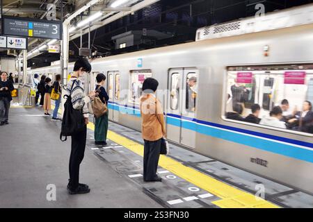 Japanese commuters wait patiently in line at the Tokyo underground Stock Photo