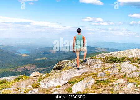 A healthy young man at the summit peak of Mount Spokane State Park looking over the valleys and lakes of Spokane, Washington State area. Stock Photo