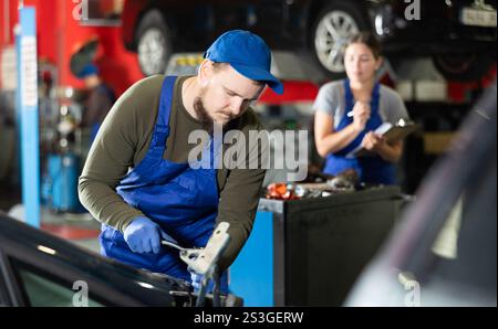 Professional mechanic man in uniform repairing car in auto repair garage Stock Photo