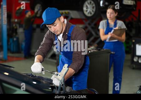 Professional mechanic man in uniform repairing car in auto repair garage Stock Photo