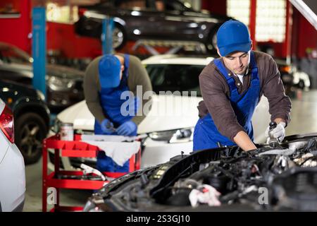 Professional mechanic man in uniform repairing car in auto repair garage Stock Photo