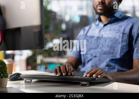 Data scientist typing on keyboard, creating machine learning models that can process and analyze data to improve and automate decision making processes. Close up of man programming in office using PC Stock Photo