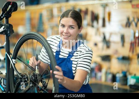 Young woman worker oiling bicycle wheel Stock Photo