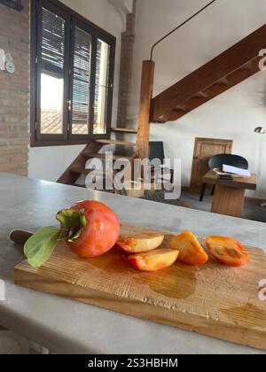 Cut persimmons on a wooding cutting board in a Spanish farmhouse Stock Photo