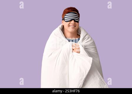 Handsome young happy man with blanket and sleeping mask on purple background Stock Photo