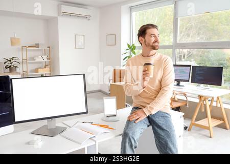 Male programmer drinking coffee in office Stock Photo