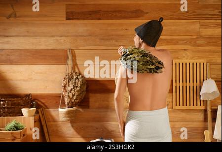 Young man beating himself with whisk in sauna, back view Stock Photo