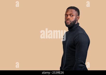 Studio portrait of a serious young man wearing black turtleneck posing on a beige background Stock Photo