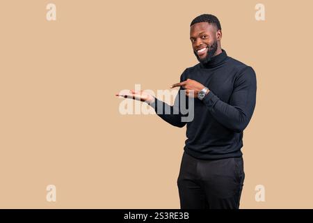 Cheerful businessman pointing at his open hand presenting something on a beige background Stock Photo