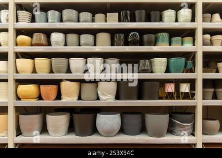 Variety of colorful ceramic and plastic flower pots on the shelf in a plant store. Shopping for trendy pot flowers and home interior design concept. Stock Photo