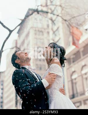 Bride and groom standing under a confetti shower in a New York street Stock Photo