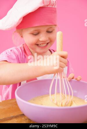 Smiling young girl whisking cake mix Stock Photo