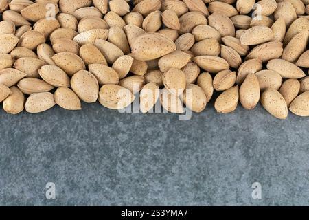 Heap of raw peeled almonds on a gray background, top view. copy space. Pattern of almond seeds. Nutty background. Stock Photo