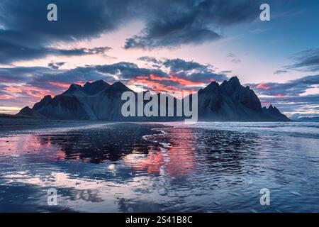 Dramatic landscape of sunset sky over volcanic Vestrahorn mountain reflecting on black sand beach in summer at Stokksnes peninsula, Iceland Stock Photo