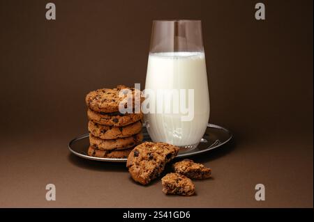 milk in a glass on a tray and cookies with chocolate next to it Stock Photo