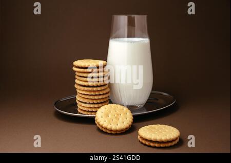 milk in a glass on a tray and cookies with chocolate next to it Stock Photo