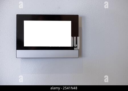 Smart home system control panel on a white wall of a living room or office. With a white screen as a blank background. Stock Photo