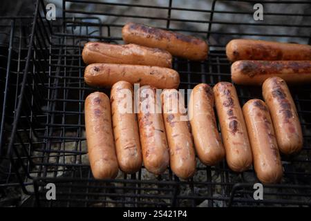 Sausages on a picnic. Roasting meat on coals. Cooking food on fire. Recreation in nature. Stock Photo