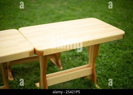 A wooden table on green grass. Empty wooden table. Furniture for relaxing outside. A place for lunch in summer. Stock Photo
