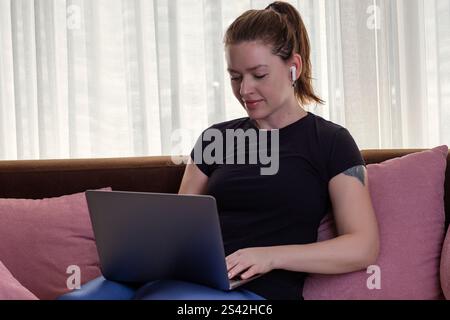 Attractive woman using laptop and wireless headphones at home Stock Photo