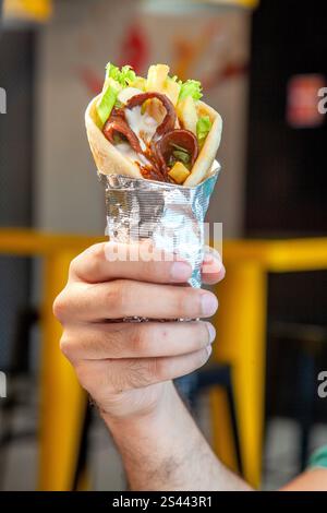 Prime beef thinly sliced doner wrap in pita bread holding in male hand. Stock Photo