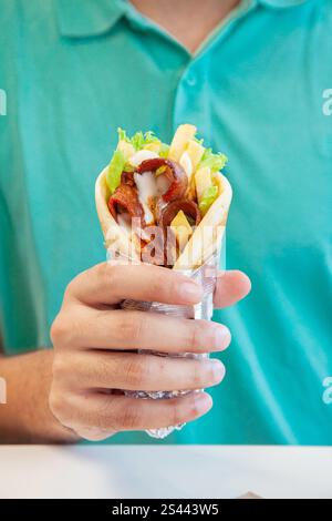 Prime beef thinly sliced doner wrap in pita bread holding in male hand wearing a green shirt. Stock Photo