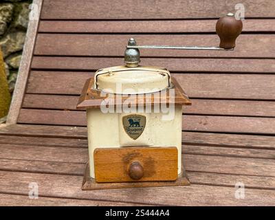 Vintage coffee grinder on a wooden bench outdoors highlighting its rustic charm and detailed craftsmanship Stock Photo