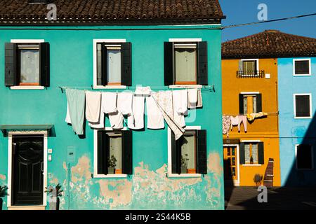 Green, yellow and blue habitations with laundry drying on clothesline in Murano Stock Photo