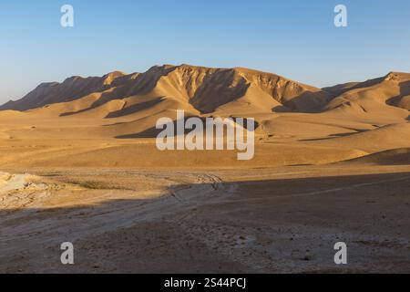 Expansive dunes stretch across the landscape of Kunduz Province, revealing the natural terrain and mountainous backdrop under clear skies. Stock Photo