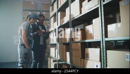 Multiethnic Inventory Specialists Scan Parcels with E-Commerce Online Orders, Check Inventory Using Tablet Computer in Warehouse Retail Facility. Logistics Distribution Center, Postal Delivery Service Stock Photo