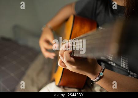 An acoustic guitar is played, in a photo with a bokeh feel that focuses on the fingers and frets Stock Photo